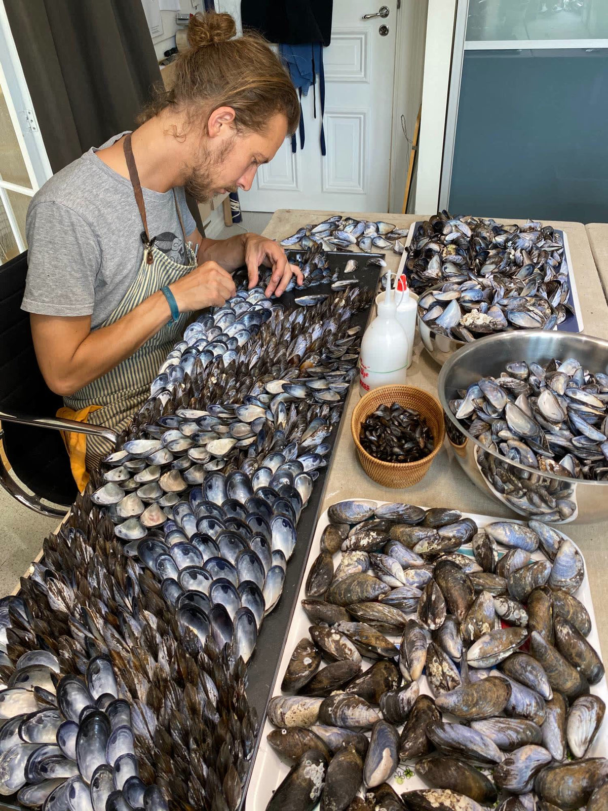 Buster Eriksson laying blue mussel shells in rows on a panel in the studio
