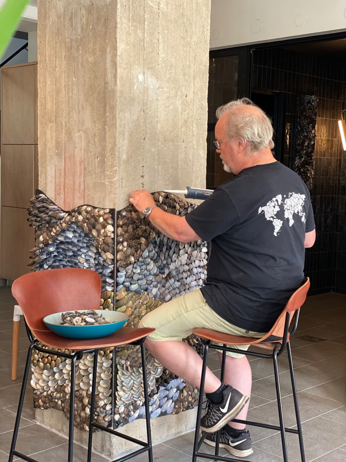 Mikael Hjärtsjö gluing limpets and blue mussels where two panels meet on the column