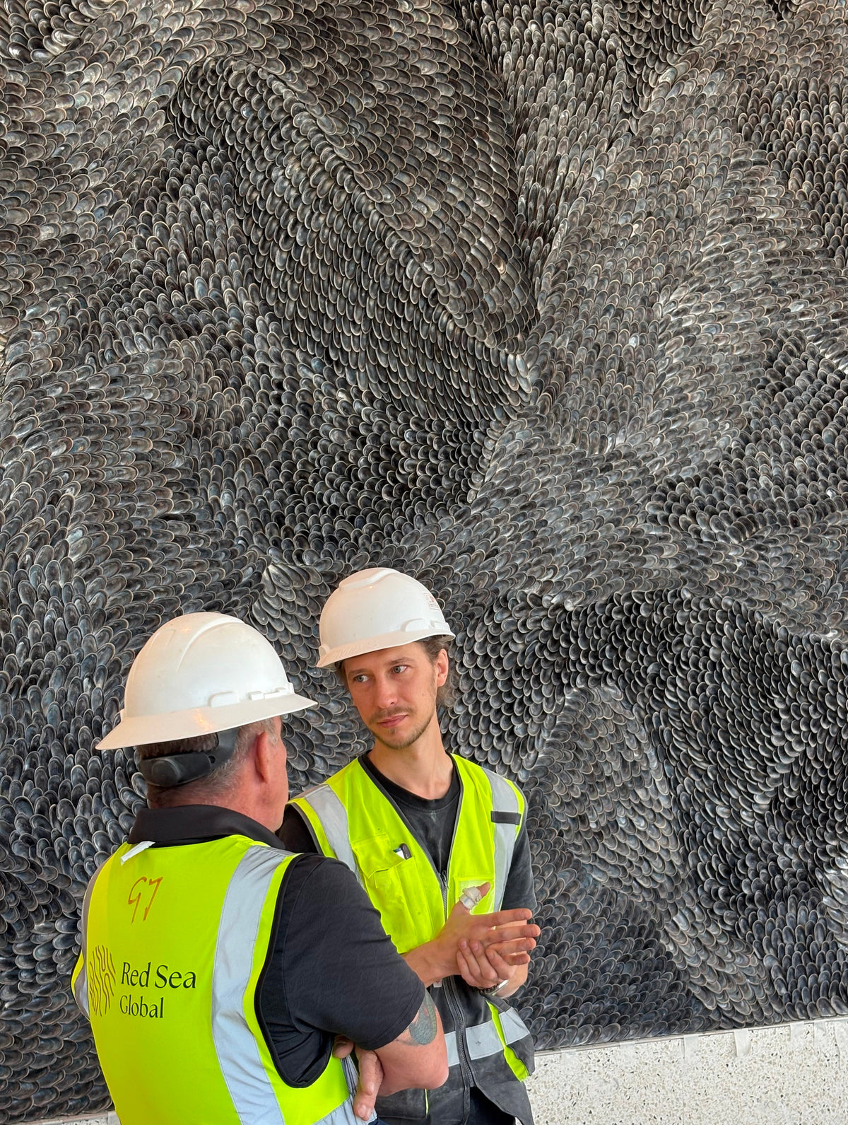 Buster Eriksson in discussion with a Red Sea Global representative in front of the wall