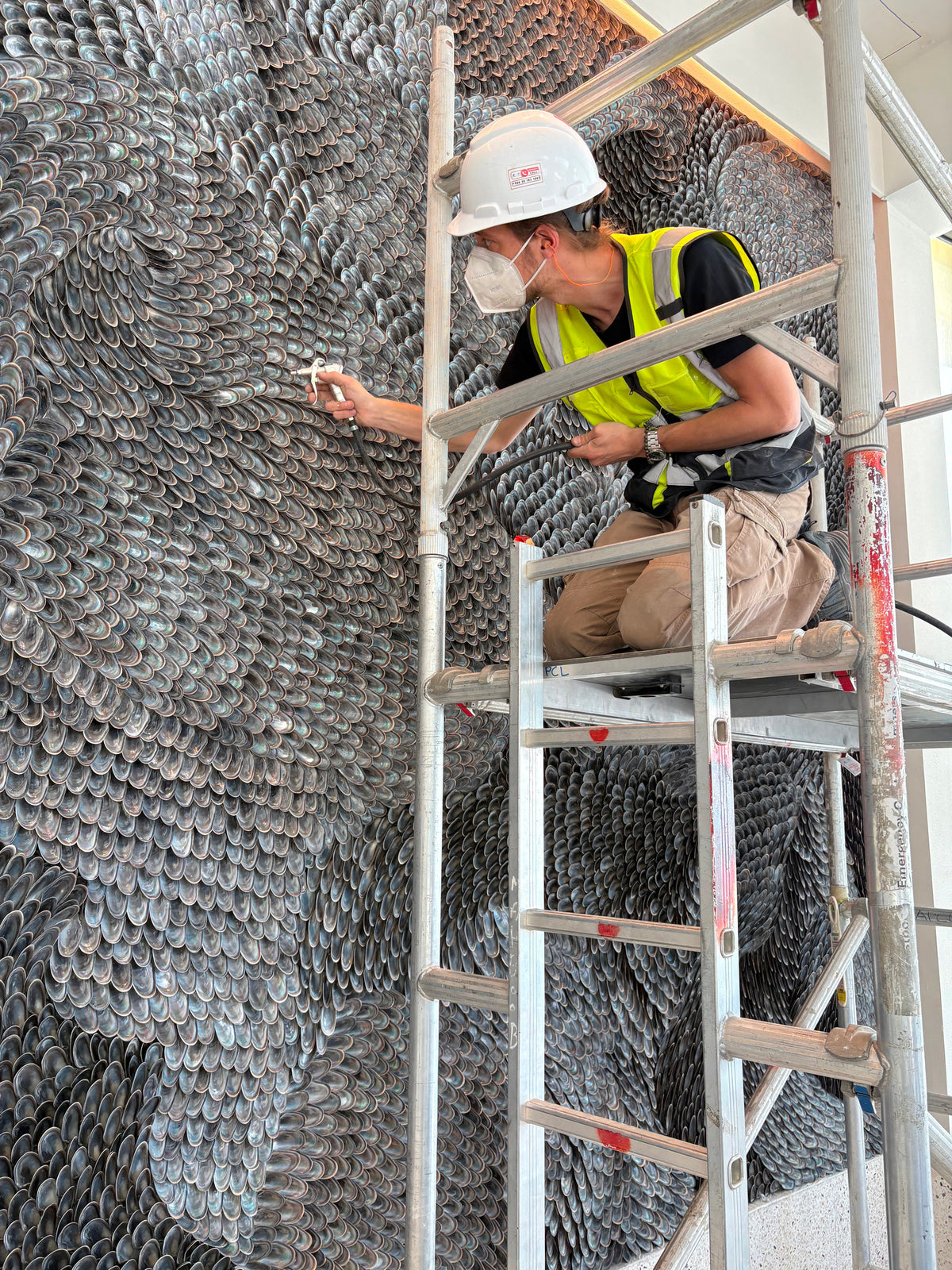 Buster Eriksson on a ladder cleaning the finished wall with compressed air