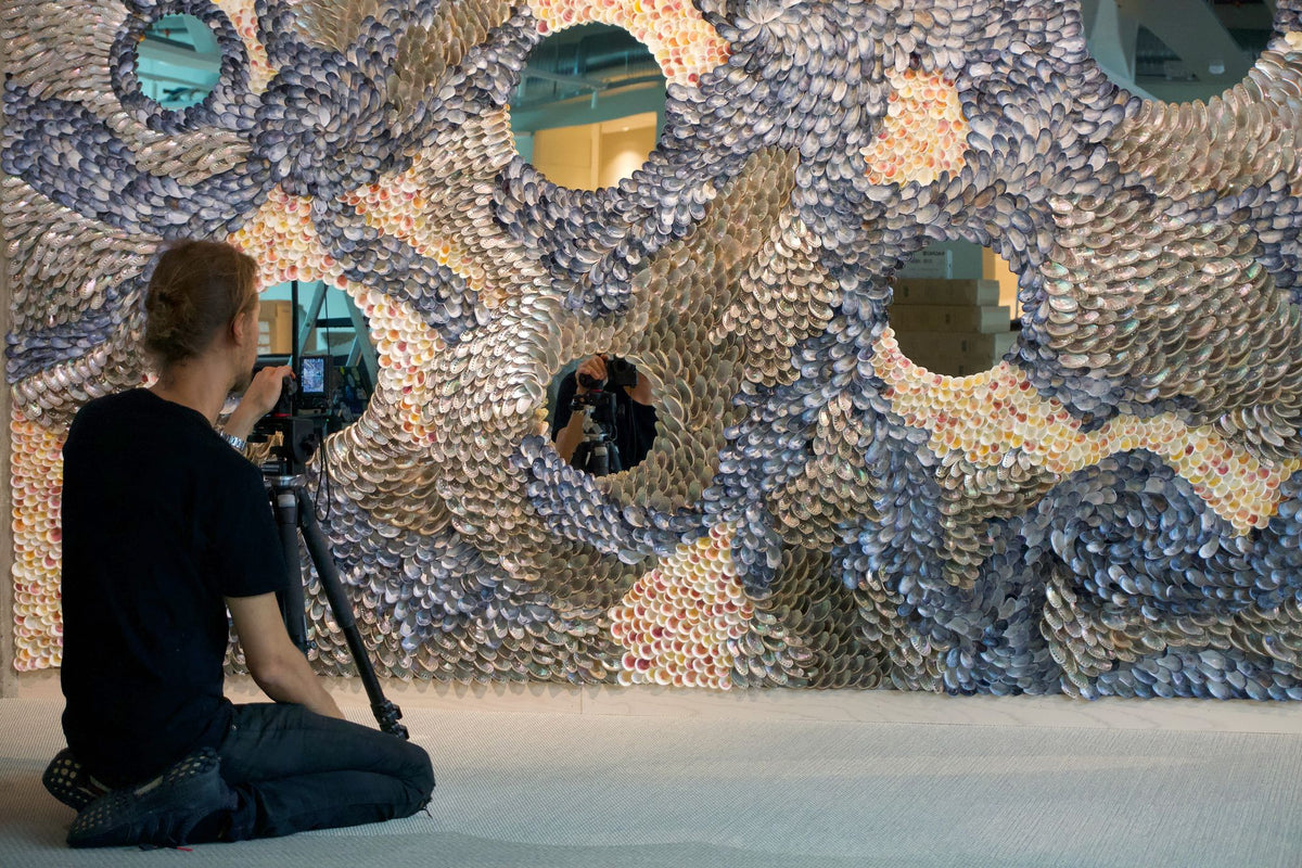 A photographer filming the finished shell wall of The Flow and its round mirrors